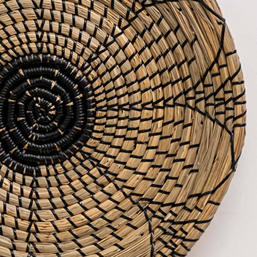 Closeup of handwoven seagrass basket showing intricate black circular woven weave texture for living room wall art decor.