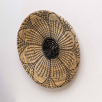 Side view of handwoven seagrass wall basket with black petal pattern for living room entryway and bedroom gallery wall decor.