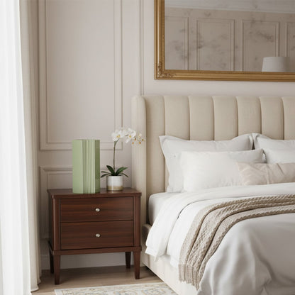 Green ribbed ceramic vase styled on a bedside table in an elegant bedroom with upholstered bed soft lighting and neutral decor accents.