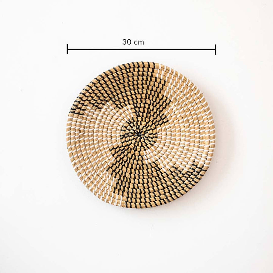 Spiral pattern black and beige woven seagrass wall hanging basket plate featuring a size line indicator on white.