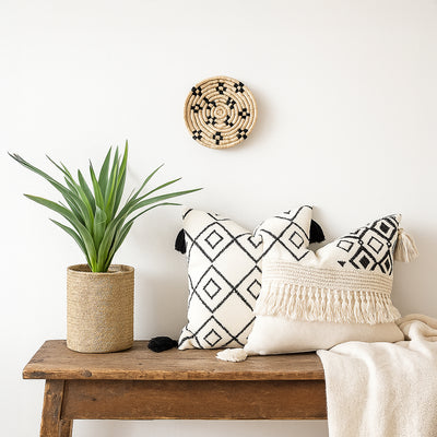 Small woven wall basket placed above wooden bench with plant and cushions adding cozy handcrafted charm to living room Decor.