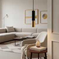 Black and gold metal pendant light above side table enhancing modern living room decor with ambient lighting.