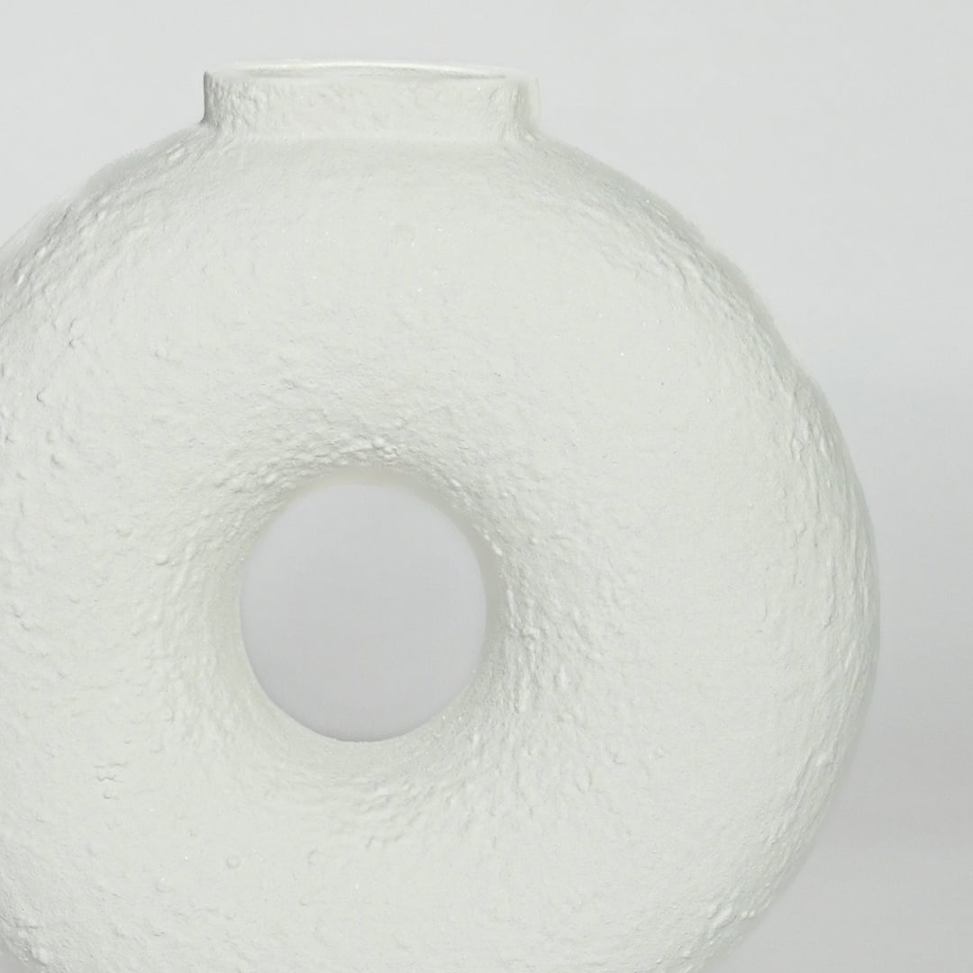 Close view of white ceramic donut vase highlighting textured surface and smooth circular center opening.