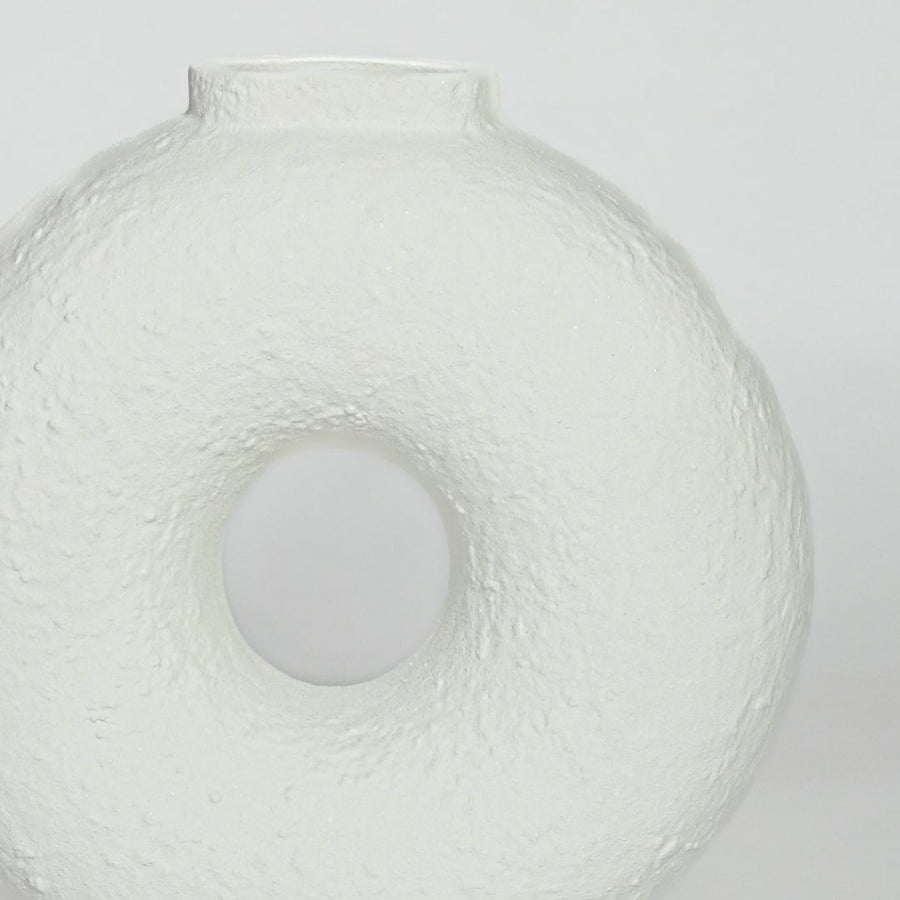Close view of white ceramic donut vase highlighting textured surface and smooth circular center opening.