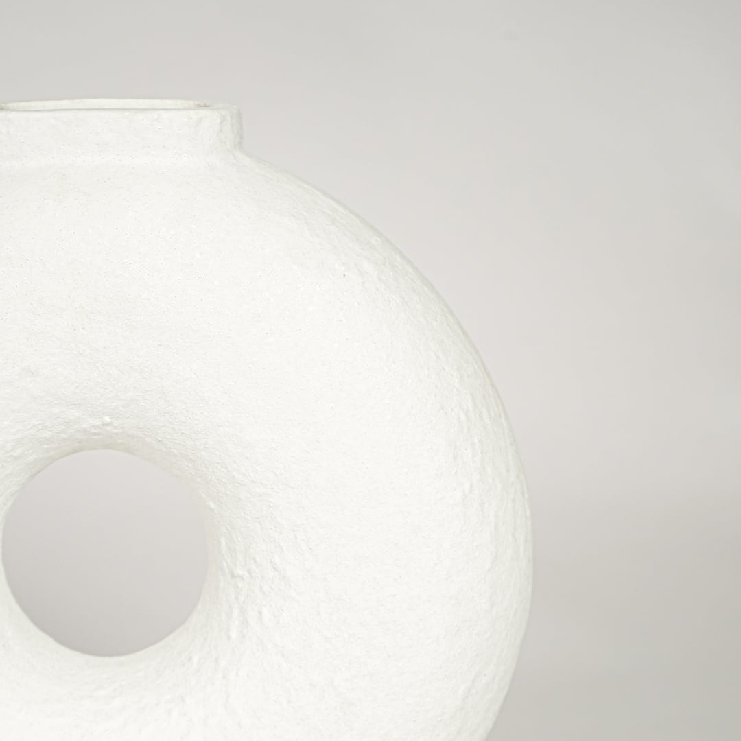 Closeup of matte white ceramic ring vase with sculptural hollow center ideal for minimalist home decor shelf styling.