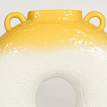 Close view of white and yellow ceramic ring vase highlighting textured body glossy rim and sculptural modern form.