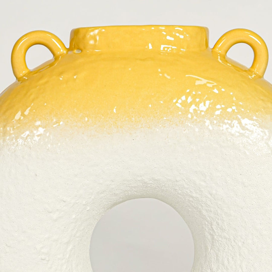 Close view of white and yellow ceramic ring vase highlighting textured body glossy rim and sculptural modern form.
