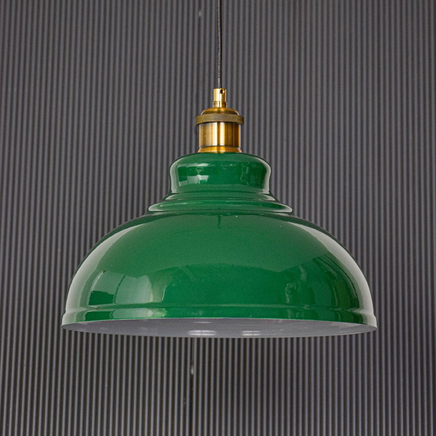 Green metal pendant ceiling light displayed on black background turned off highlighting glossy dome shade gold holder and clean modern design.