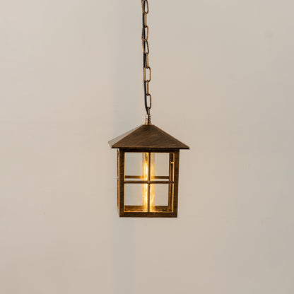 Gold metal hanging outdoor lantern with square glass enclosure glowing on white background suitable for porch entrance and exterior decor lighting.