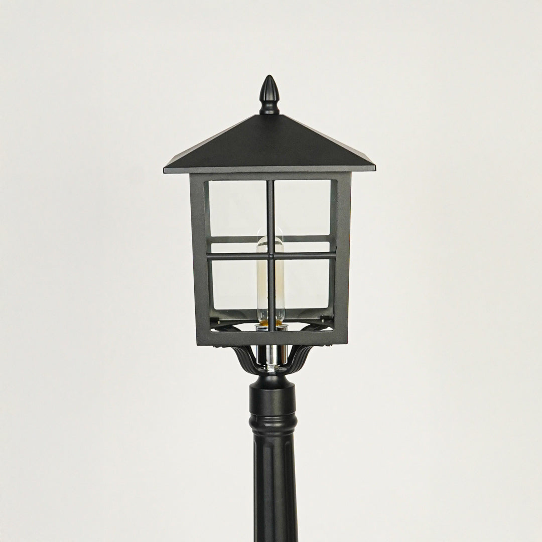 Close view of black outdoor lamp post with glass enclosure showcasing durable weather resistant exterior lighting design.