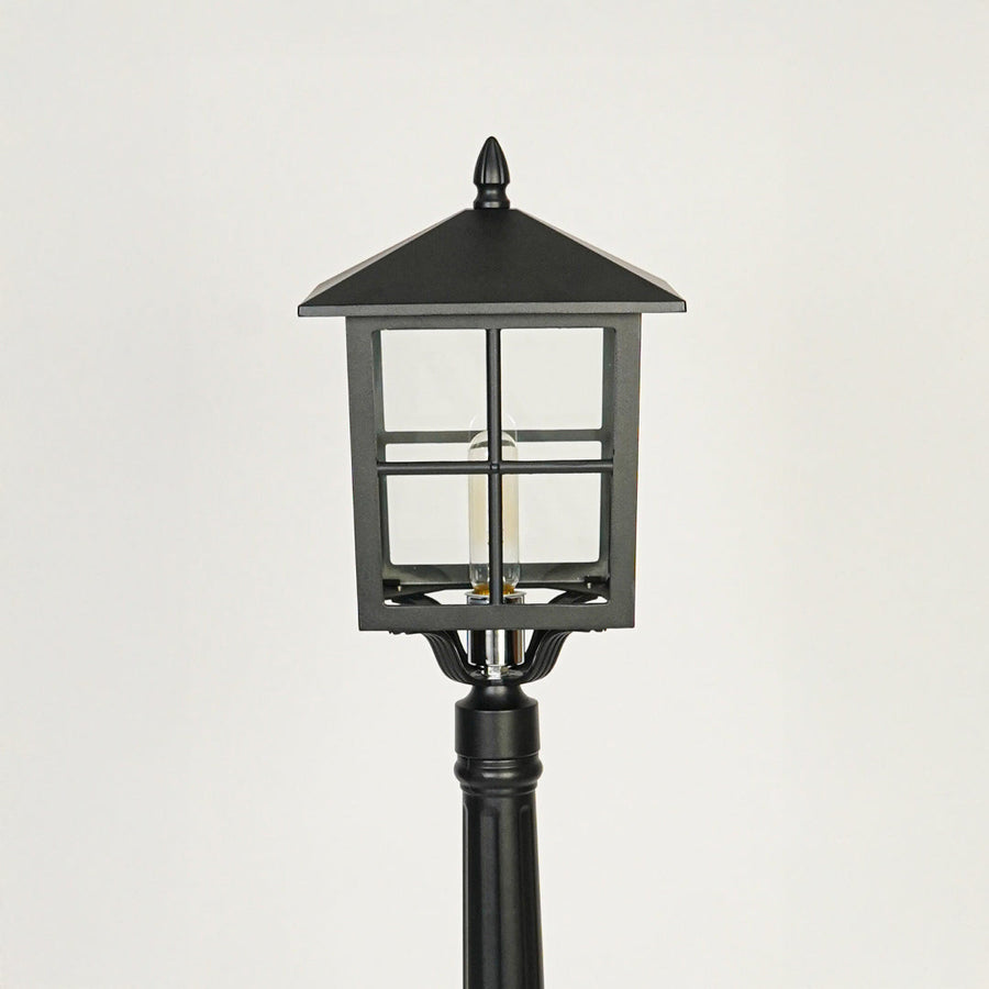 Close view of black outdoor lamp post with glass enclosure showcasing durable weather resistant exterior lighting design.