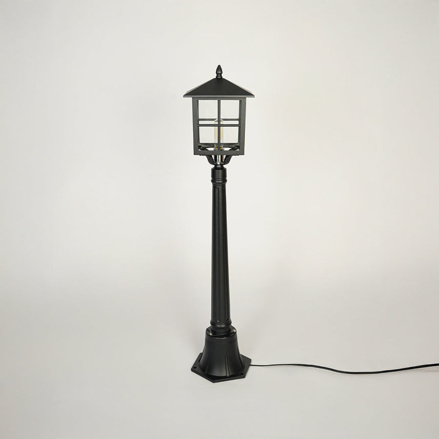 Minimal outdoor pole light with traditional lantern style and black metal body on clean background ideal for garden or patio lighting.