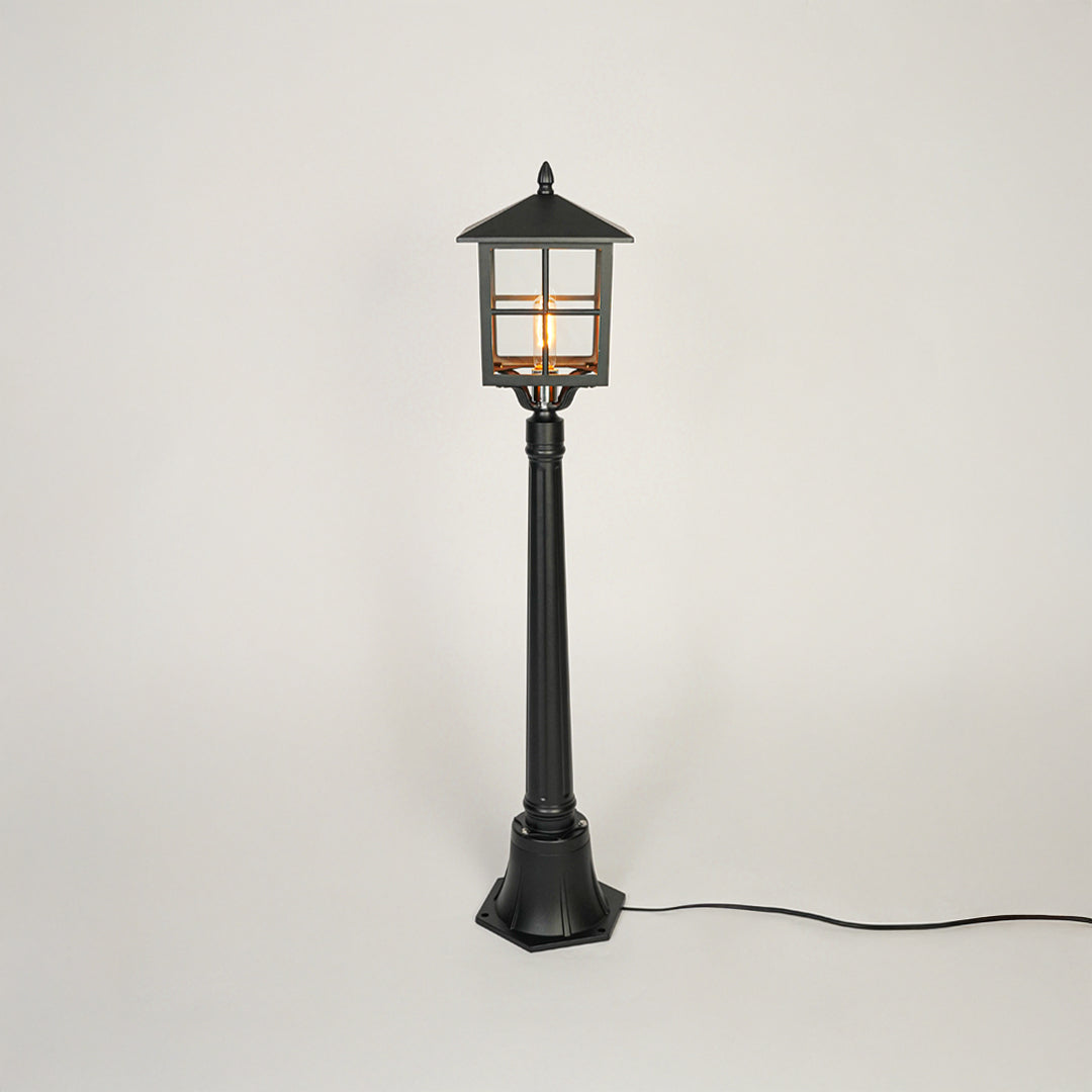 Classic black metal garden lamp post with clear glass panels on neutral background perfect for outdoor pathway or driveway lighting.