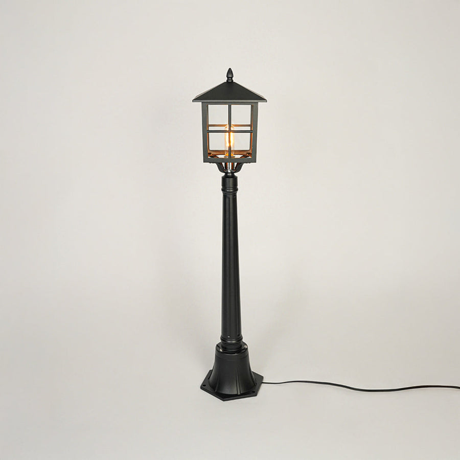 Classic black metal garden lamp post with clear glass panels on neutral background perfect for outdoor pathway or driveway lighting.