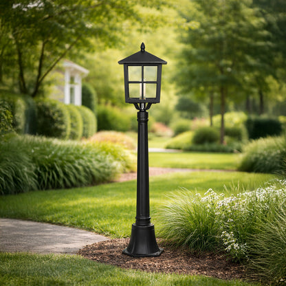 Black outdoor garden pole light with classic lantern design installed on pathway in green landscape ideal for exterior lawn or garden lighting.