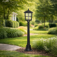 Black outdoor garden pole light with classic lantern design installed on pathway in green landscape ideal for exterior lawn or garden lighting.