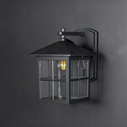 Outdoor black metal wall lantern switched off on dark background emphasizing clean lines square shape and sturdy build.