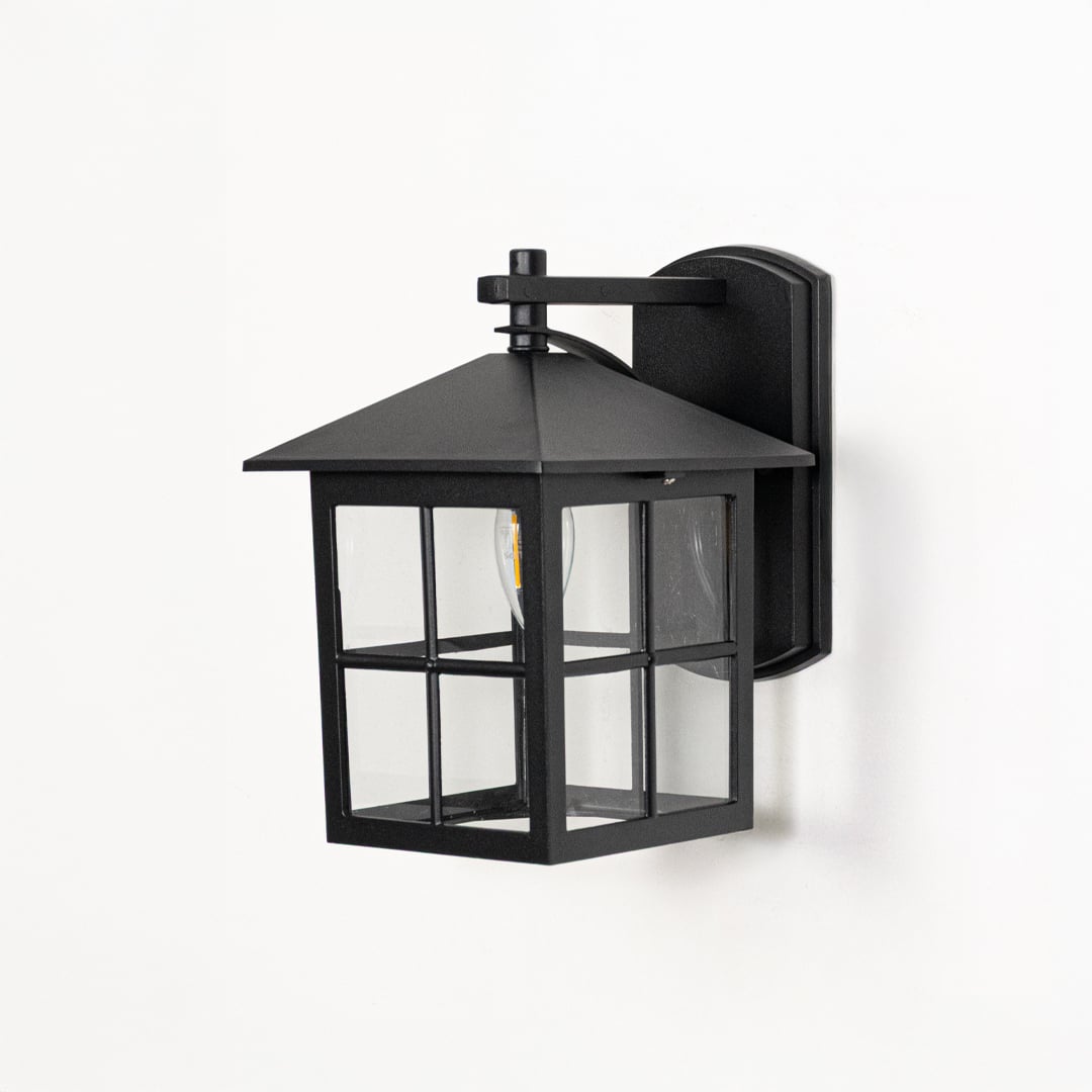 Black metal wall lantern switched off on white background highlighting square frame clear glass and modern outdoor design.