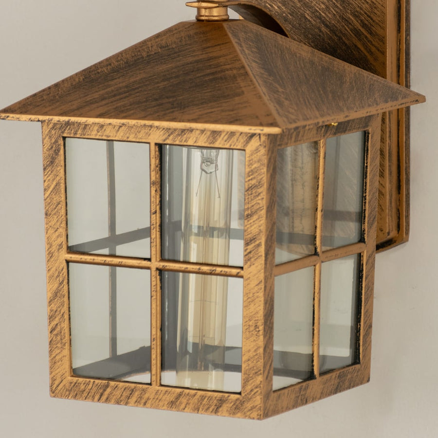 Closeup of gold metal outdoor lantern showing window pane glass and textured metal finish highlighting its rustic vintage outdoor look.