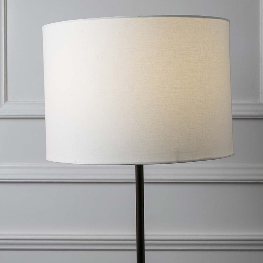 White fabric drum shade with sleek black metal stem showcasing contemporary design and refined craftsmanship.
