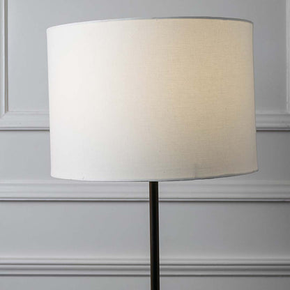 White fabric drum shade with sleek black metal stem showcasing contemporary design and refined craftsmanship.