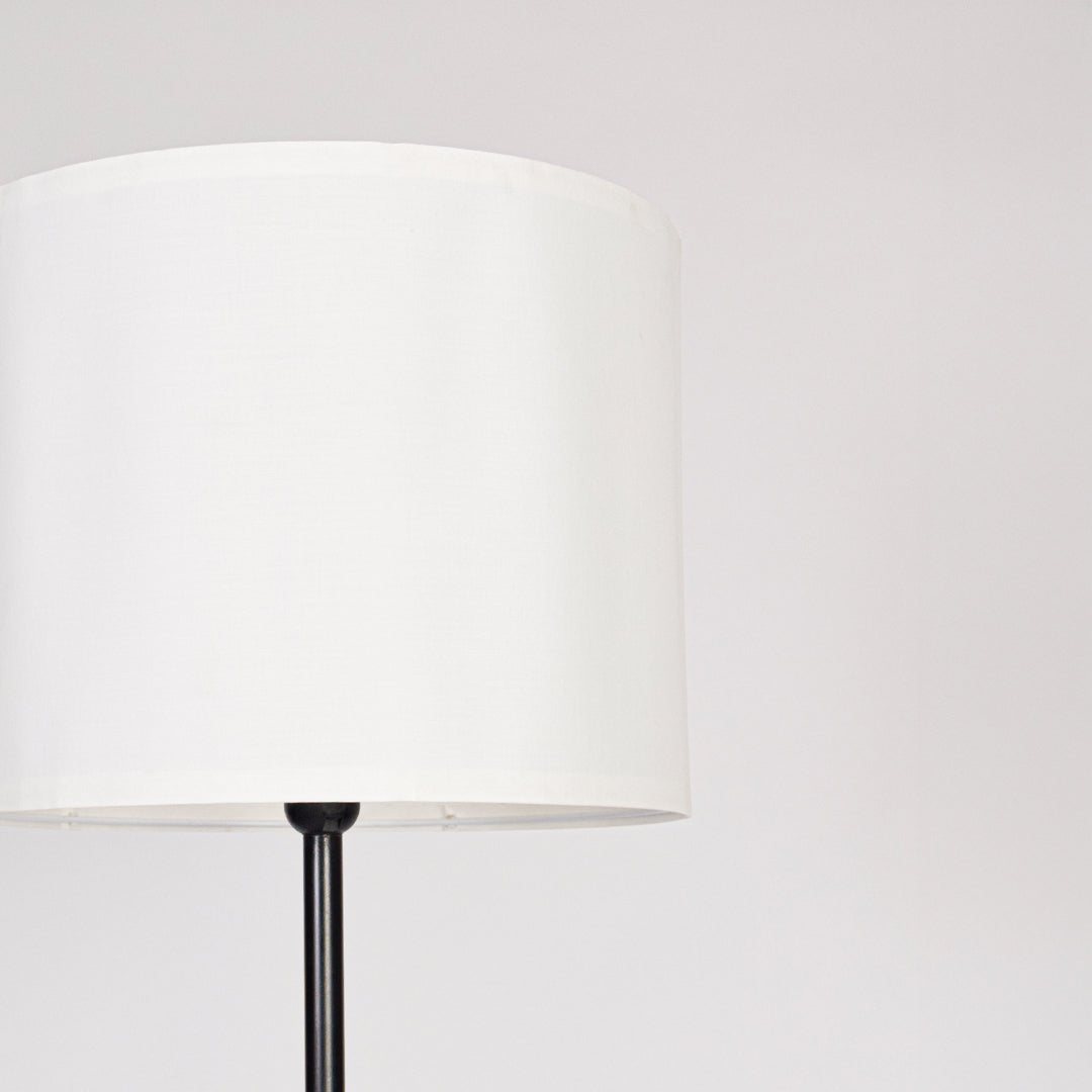White fabric drum shade with sleek black metal stem showcasing minimalist design and refined modern craftsmanship.