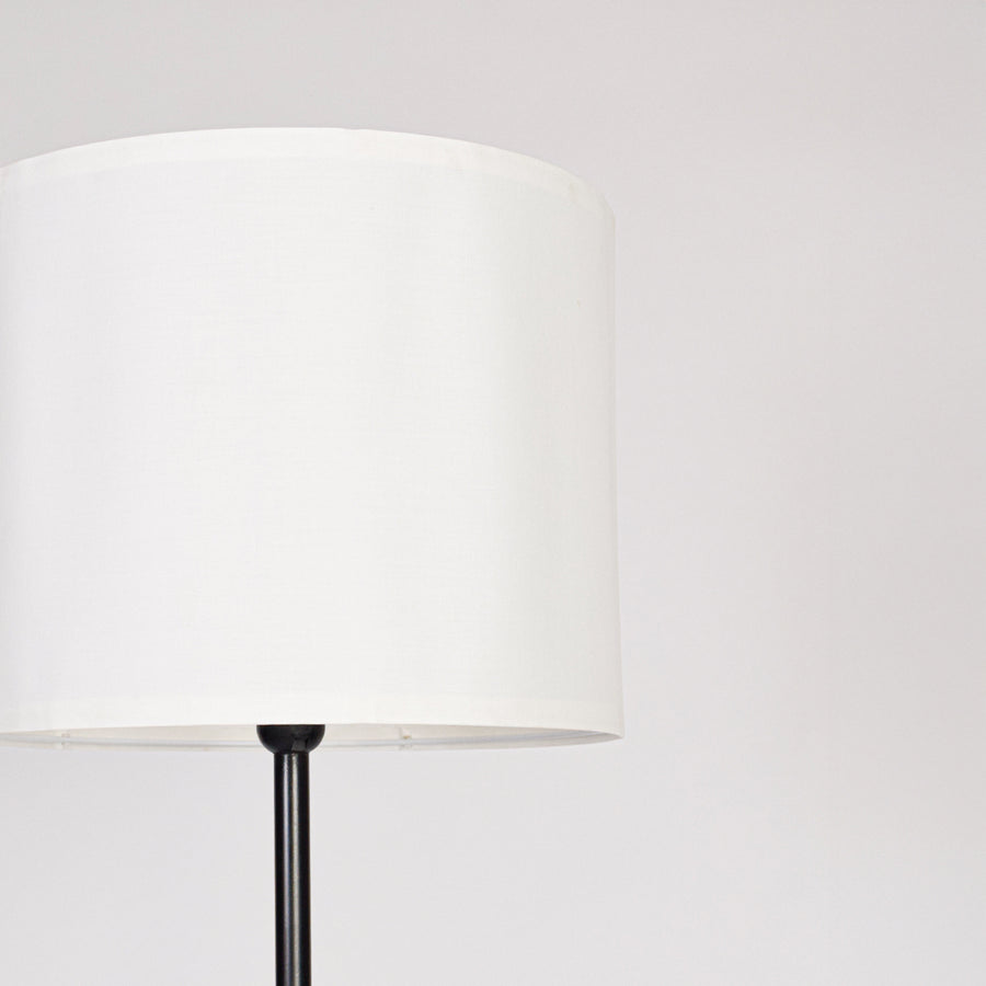 White fabric drum shade with sleek black metal stem showcasing minimalist design and refined modern craftsmanship.