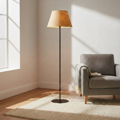 Modern black floor lamp with beige fabric shade styled in living room corner creating warm ambient lighting decor.