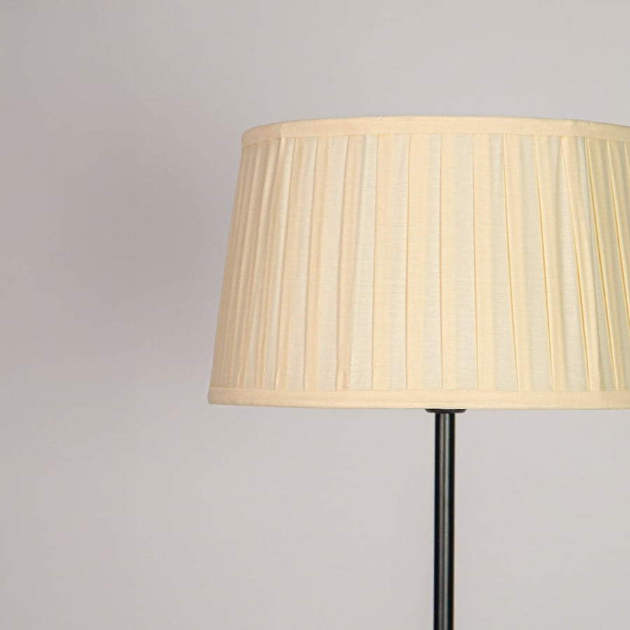 Closeup pleated cream fabric drum shade with textured detailing for soft diffused lighting in elegant interiors Decor.