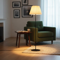 Modern black floor lamp with pleated cream fabric shade styled in minimal living room interior with soft ambient lighting.