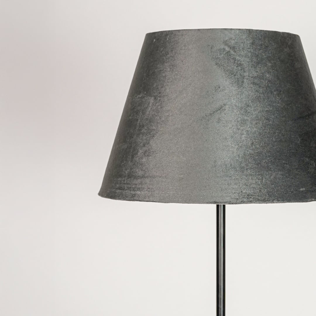Grey velvet fabric lampshade with tapered silhouette designed to create soft diffused ambient lighting.