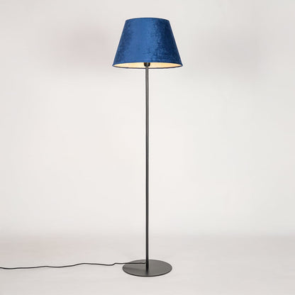 Black floor lamp illuminated through blue fabric shade casting soft diffused glow on white backdrop.