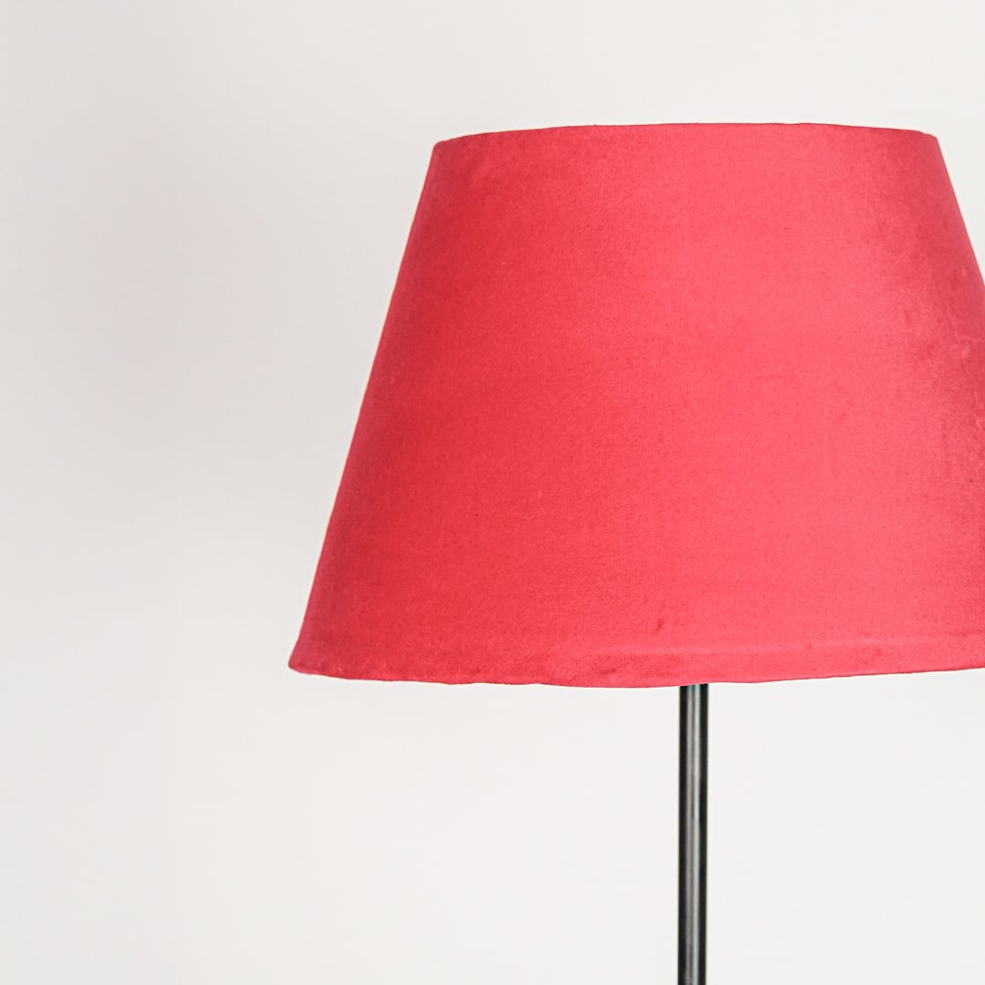Red fabric tapered lampshade designed to provide warm ambient lighting and bold decorative accent.
