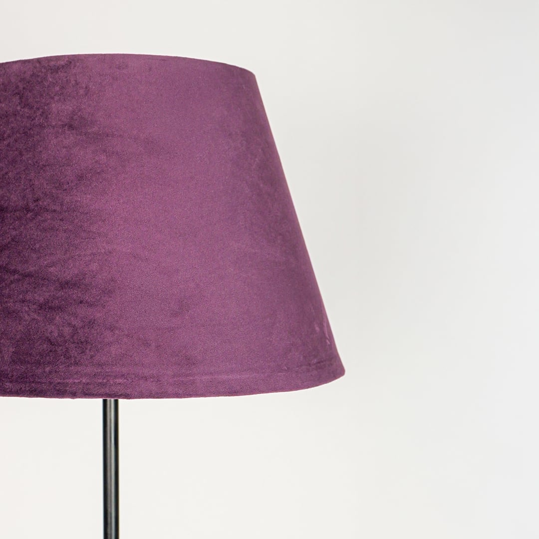 Textured purple fabric lampshade with tapered silhouette designed to softly diffuse warm ambient light.