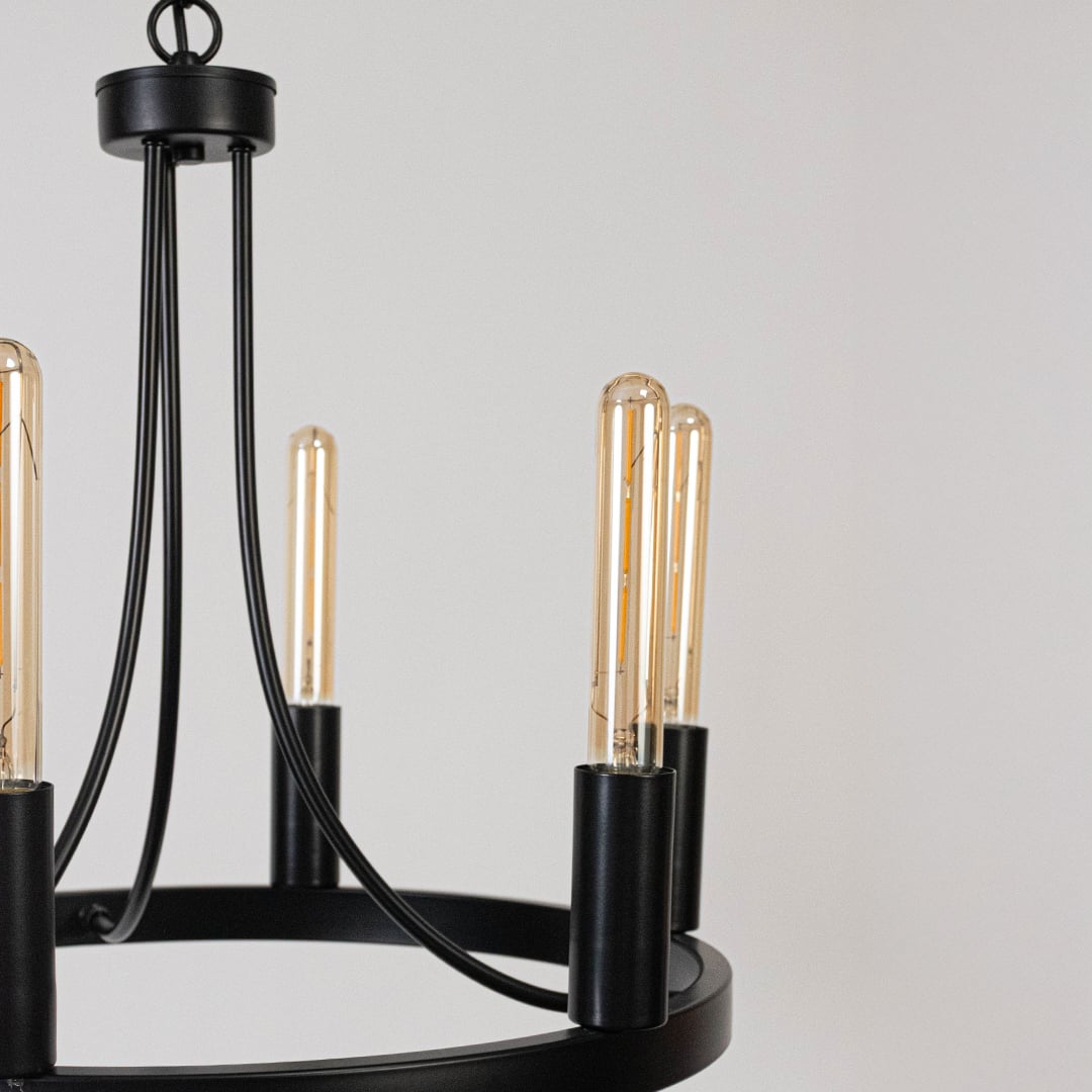 Detailed closeup of exposed vintage Edison tube bulb with black metal candle holder socket on contemporary chandelier fixture.