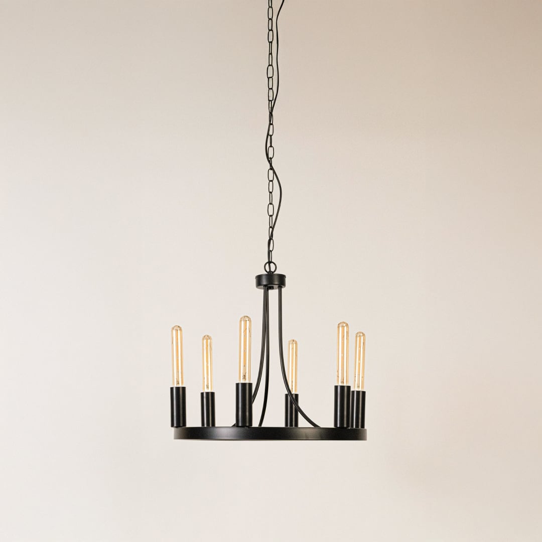 Contemporary black metal six light candelabra chandelier with chain and Edison bulb sockets turned off on white background.