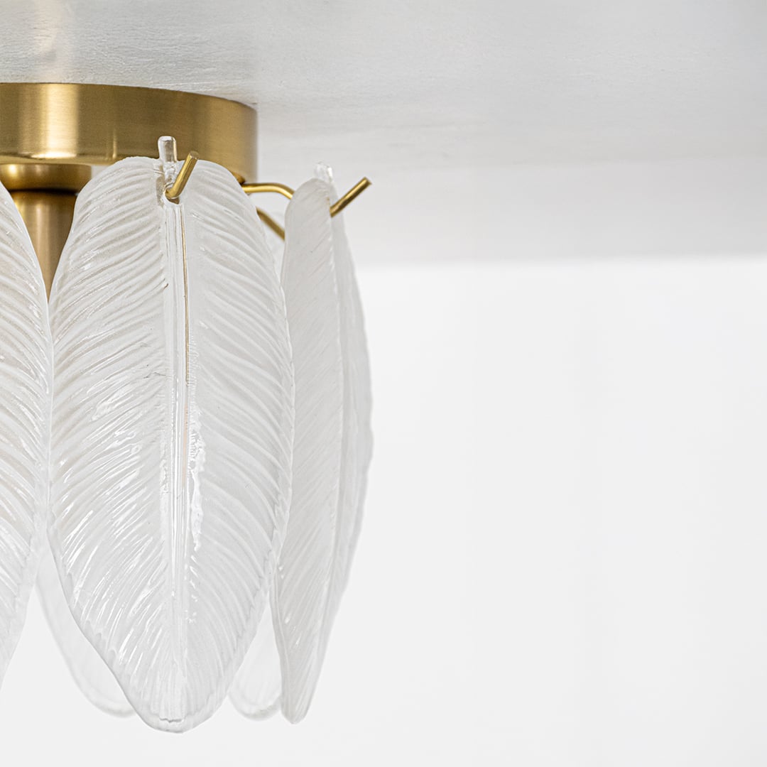Closeup of gold ceiling light featuring frosted sculpted leaf glass panels designed to add elegant decorative texture and soft ambient lighting.