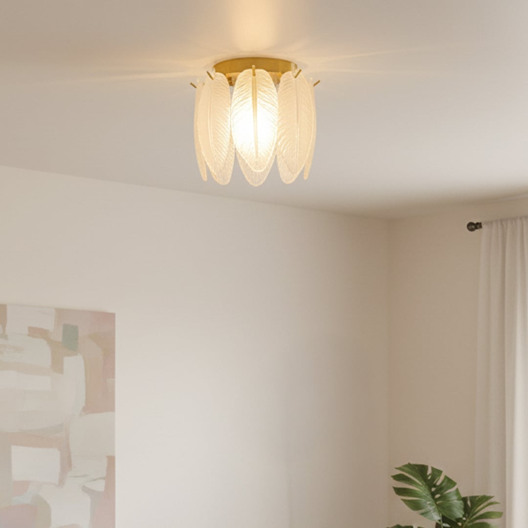 Gold metal ceiling light with frosted glass leaf panels glowing warmly in a modern living space creating a soft decorative ambient lighting effect.