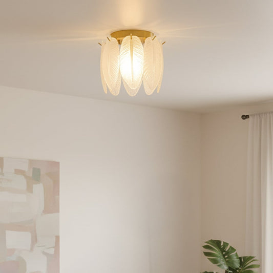 Gold metal ceiling light with frosted glass leaf panels glowing warmly in a modern living space creating a soft decorative ambient lighting effect.