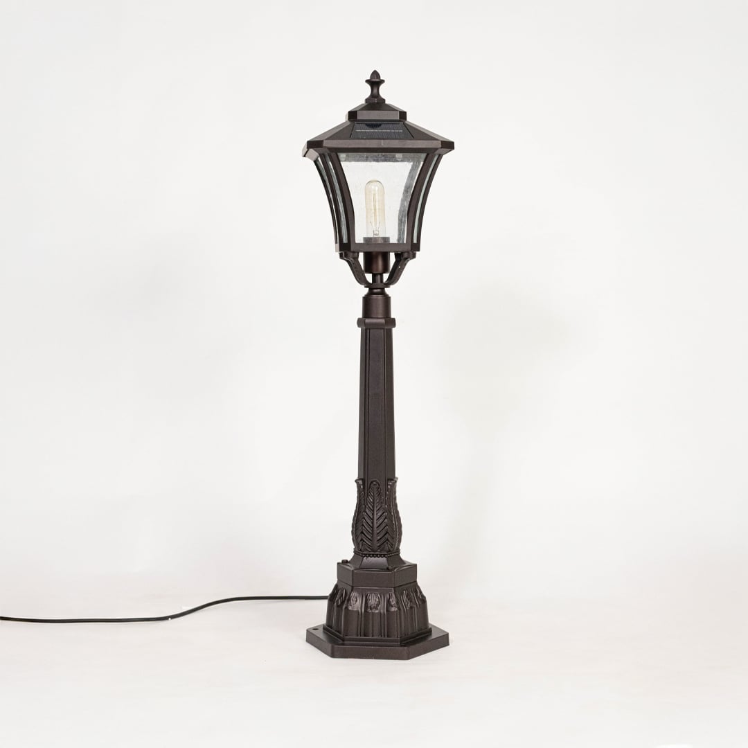 Solar pillar light with black metal frame and glass shade shown off on white background highlighting classic design.