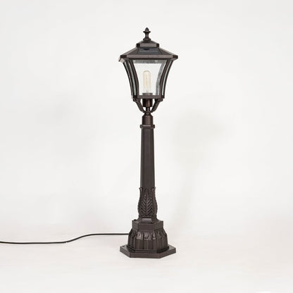 Solar pillar light with black metal frame and glass shade shown off on white background highlighting classic design.