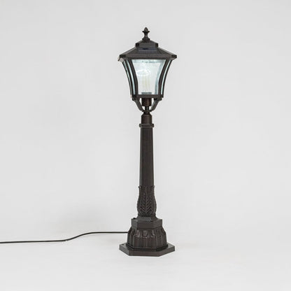 Stylish solar pillar lamp post glowing softly through clear glass shade ideal for modern outdoor garden lighting.