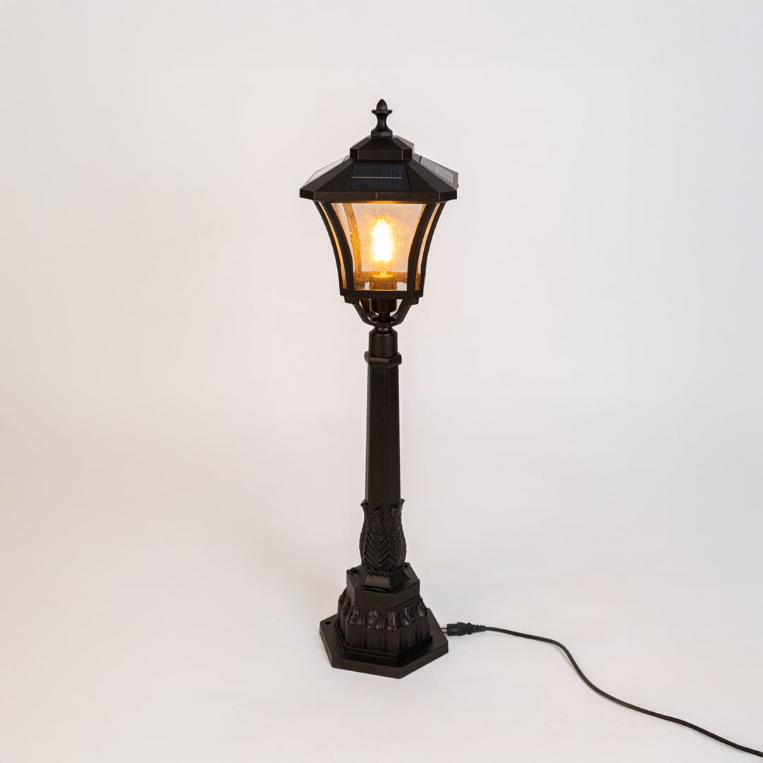 Outdoor post lamp in black metal with glass panels displayed on white background showcasing traditional garden lighting style.