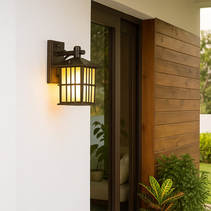 Black metal outdoor wall lantern with frosted glass panels mounted on exterior wall creating classic and durable home lighting.