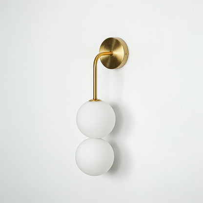 Gold wall light with dual white frosted glass globes on white background modern vertical lighting ideal for bedroom and living room decor.