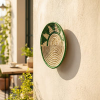 Handwoven bamboo wall decor plate in green beige tones displayed with pampas vase enhancing modern boho interior.