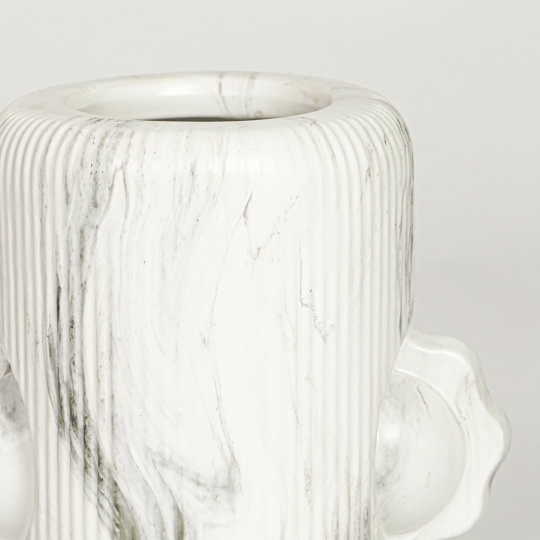 Closeup of white glazed ceramic vase with artistic facial sculpture showcasing handcrafted texture for home decor styling.