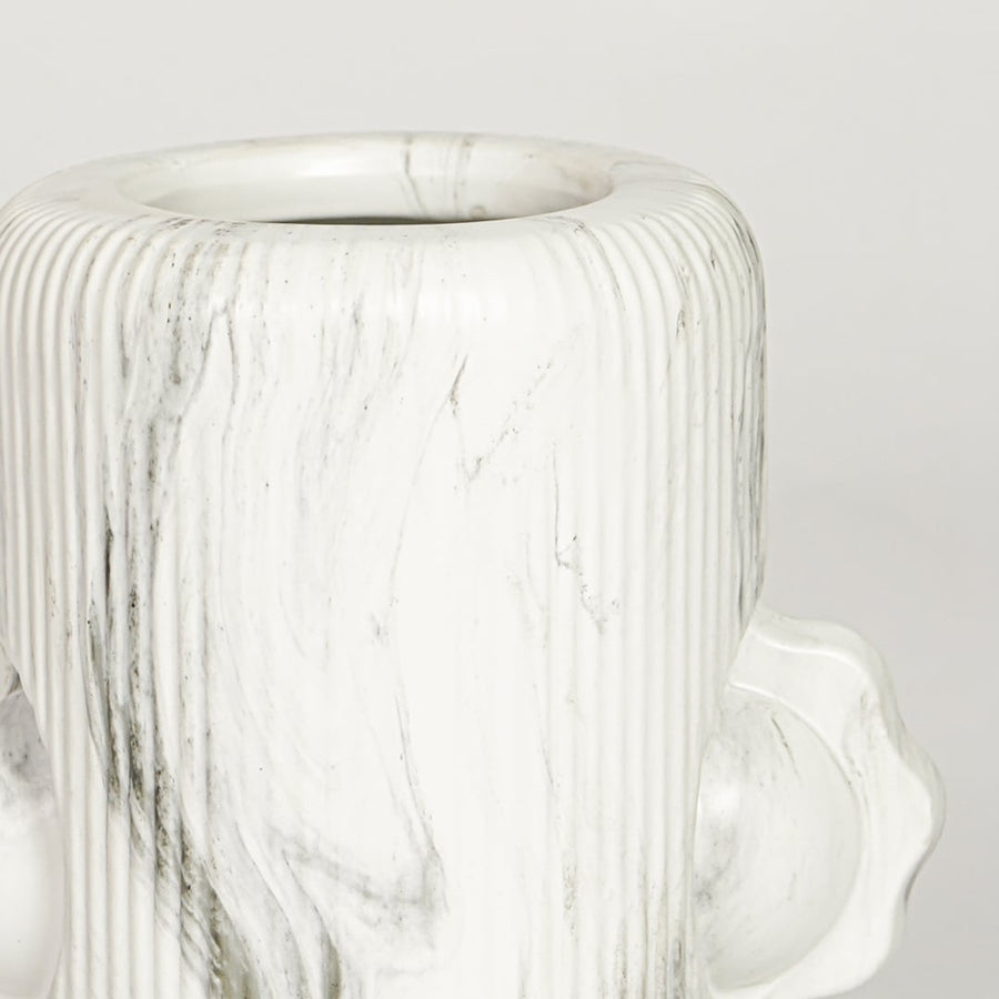 Closeup of white glazed ceramic vase with artistic facial sculpture showcasing handcrafted texture for home decor styling.
