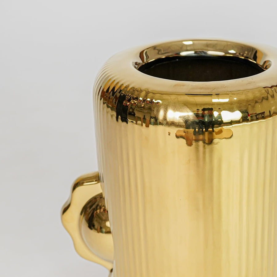 Closeup gold metal vase shiny texture detail modern decorative flower vase for table shelf console decor.