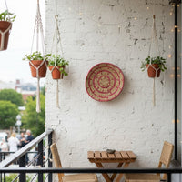 Textured botanical wall decor plate styled with planters and wooden accents creating balanced nature inspired composition for cozy modern interiors.
